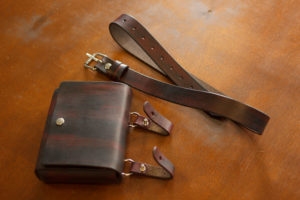 Handcrafted leather accessories for photographers displayed on a table, showcasing detailed stitching and high-quality materials