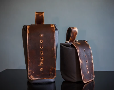 Vintage leather lens pouch and bag for photographers on reflective surface