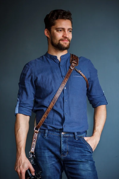 Male photographer wearing a handmade leather single camera strap across shoulder
