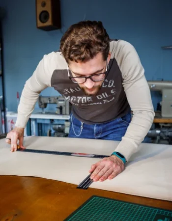Craftsman measuring natural leather for handcrafted camera accessories